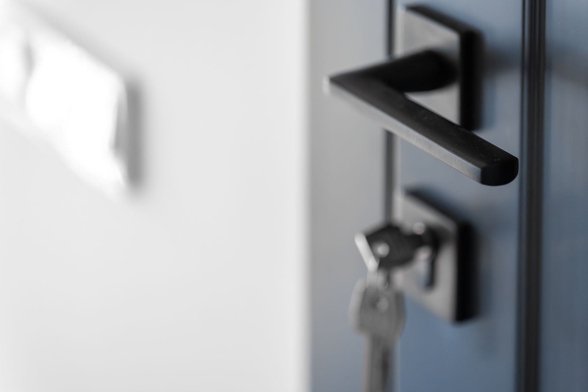 Black door handle with key inserted in a blurred doorway close-up