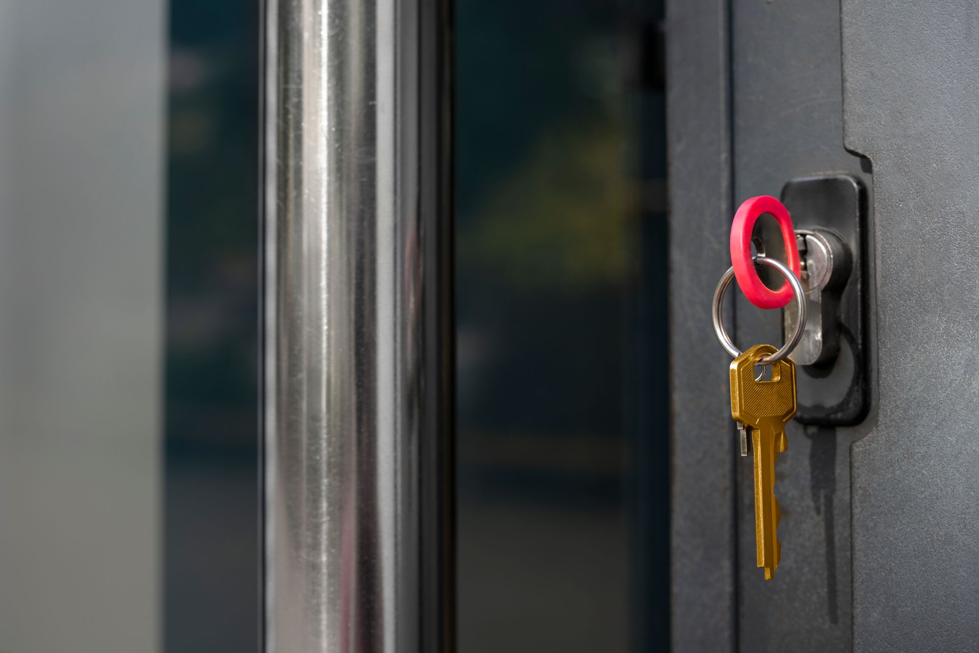 Close-up of a key inserted in a wall-mounted lock, with a red keyring.