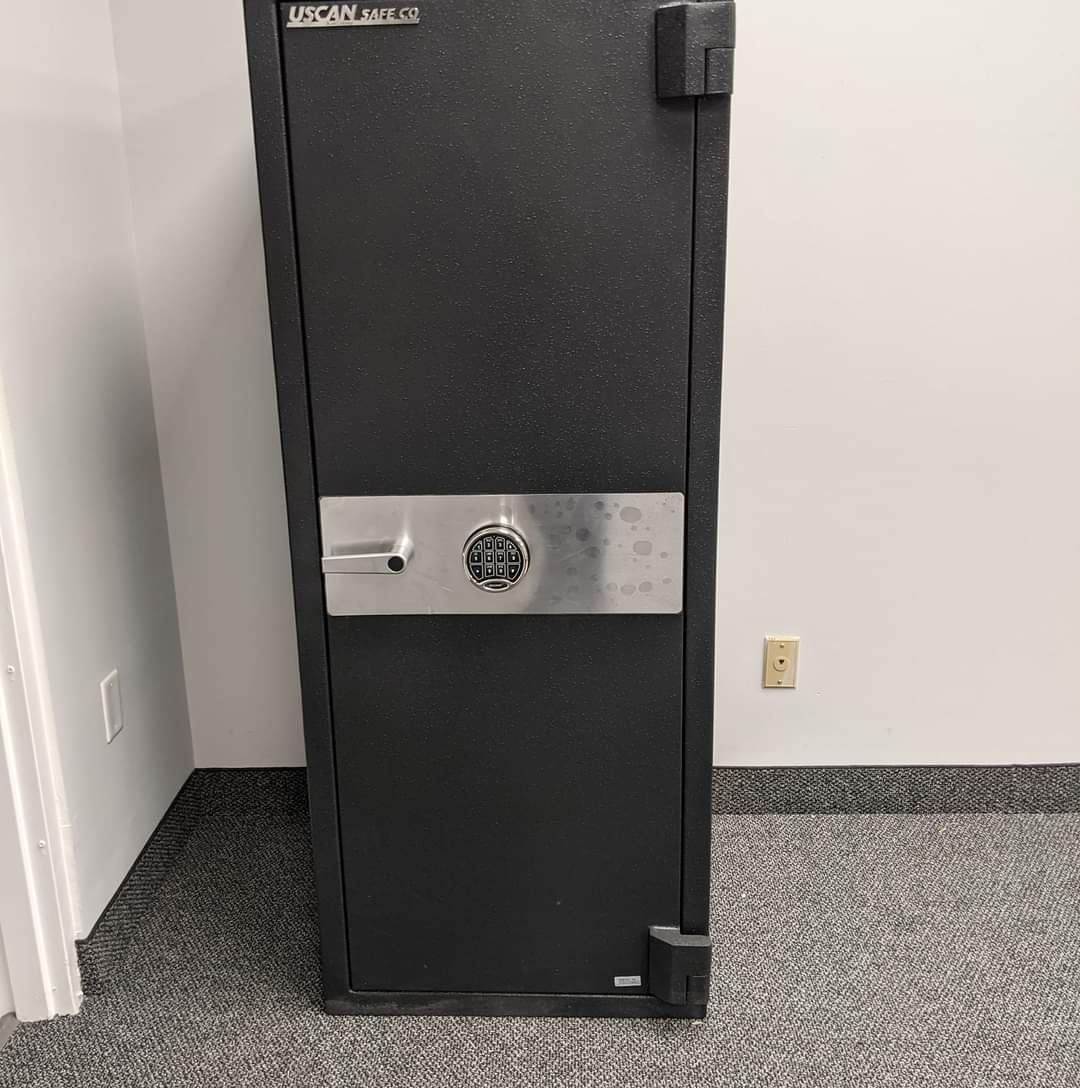 a black safe is sitting on a carpeted floor in a room .