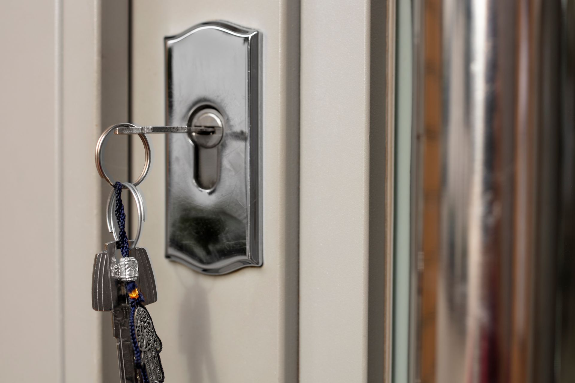 Key in a door lock on a white door; a key ring hangs with keys.