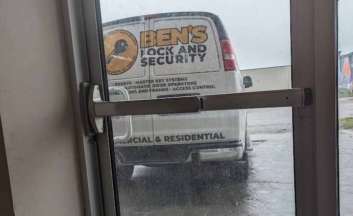 A hen 's lock and security van is parked in front of a glass door.