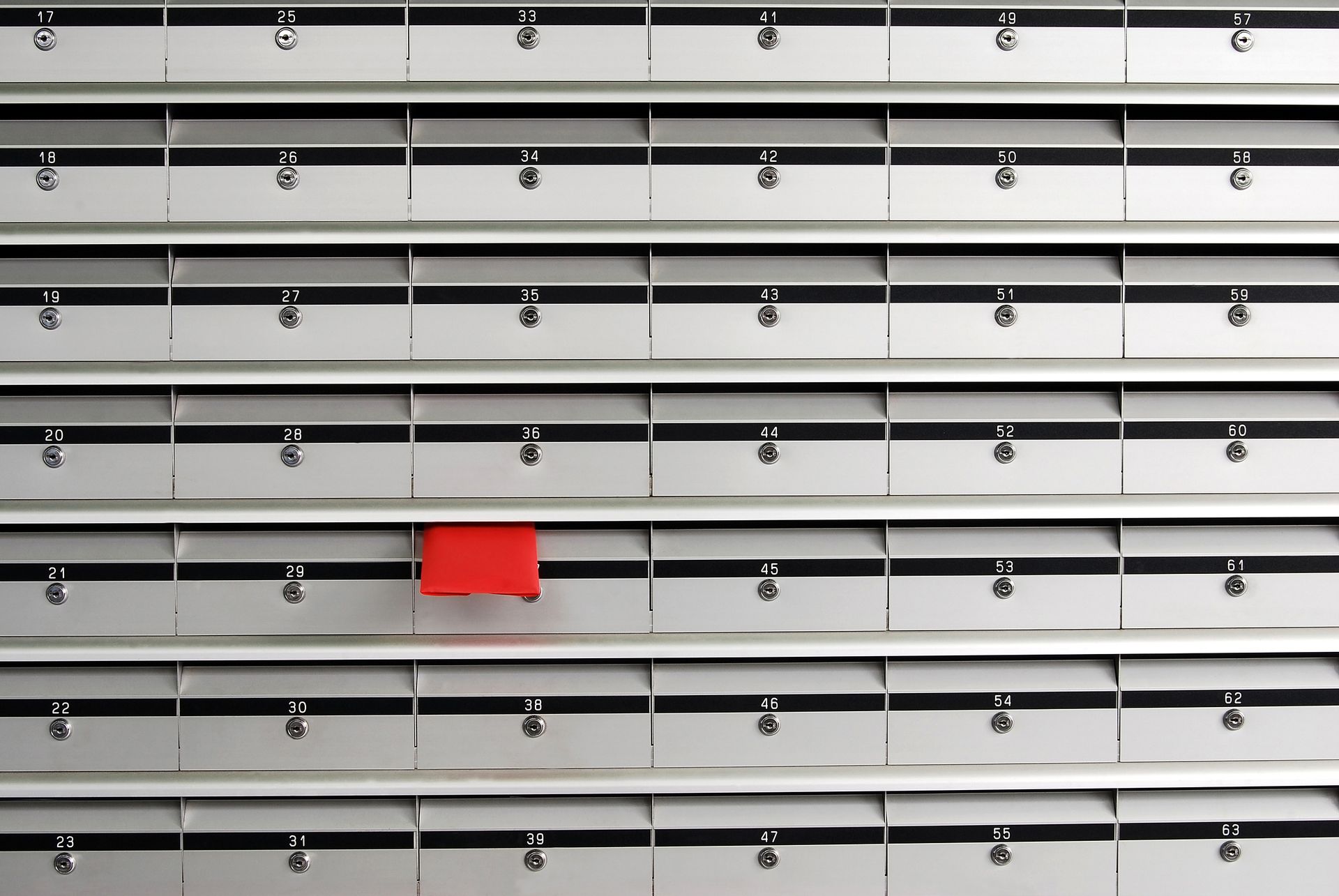 Rows of silver mailboxes with a single red mailbox open.