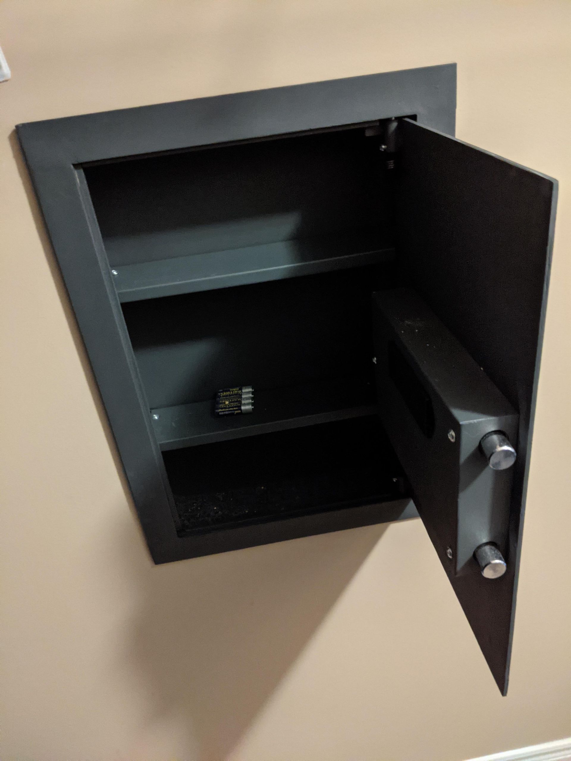 A safe is built into a wall with the door open.