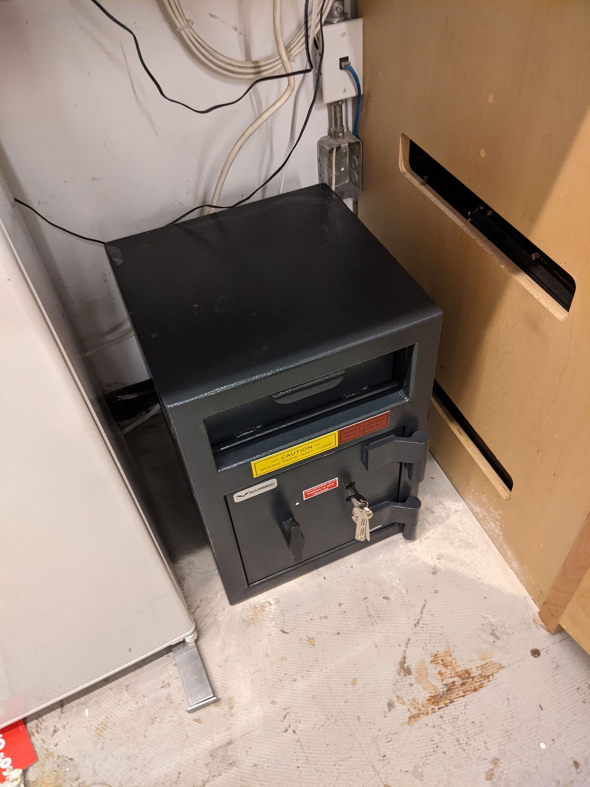 A black safe is sitting on the floor next to a wall.