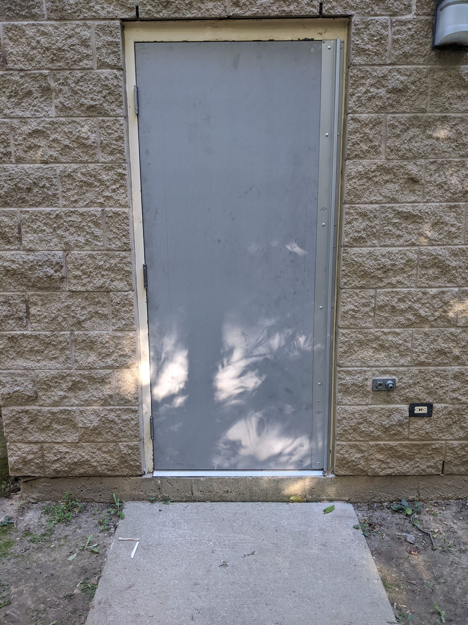 A gray door with a brick wall behind it