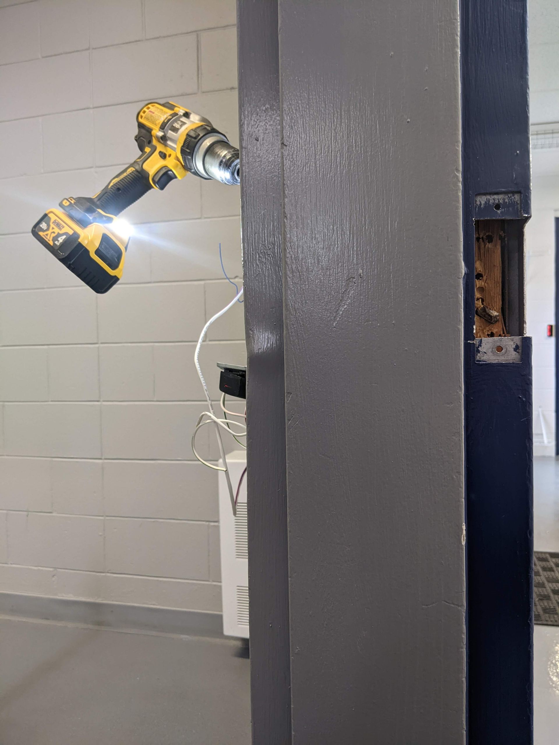 A person is using a drill to fix a door.