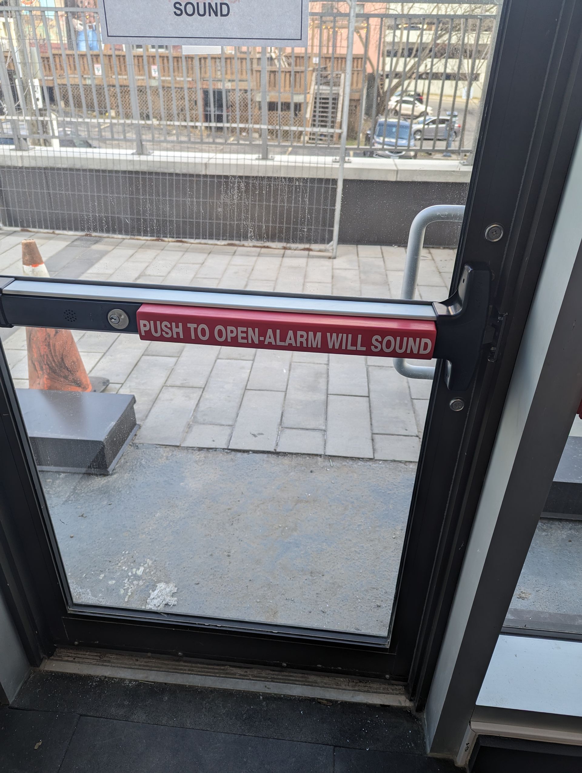 A door with a red sign that says push to open alarm will sound