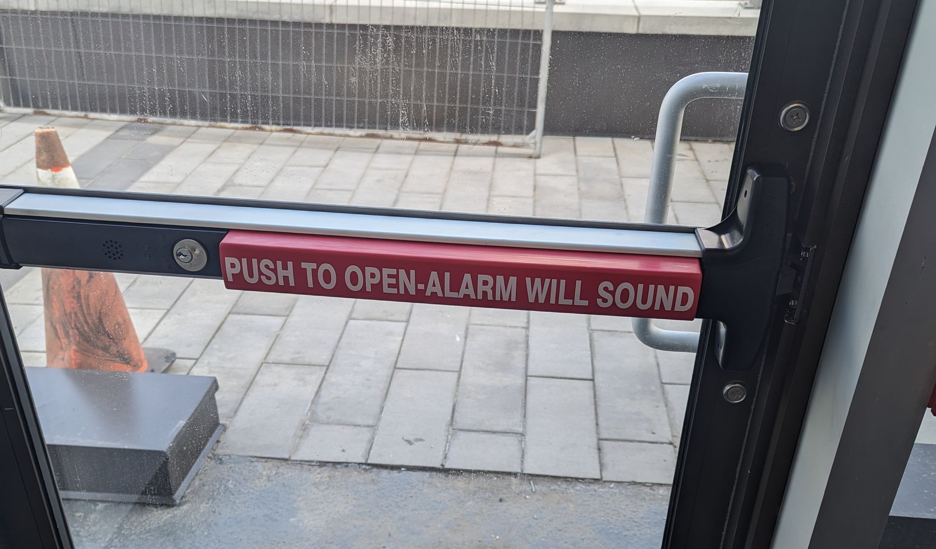 A door with a sign that says push to open alarm will sound