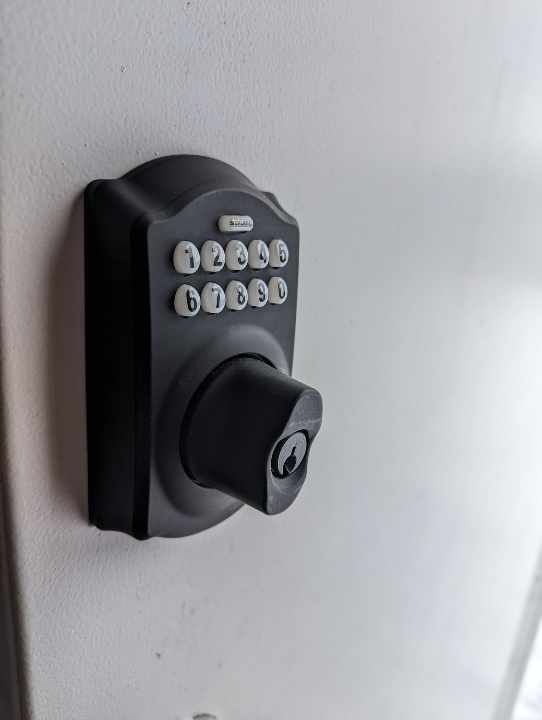 A close up of a digital door lock on a white wall.