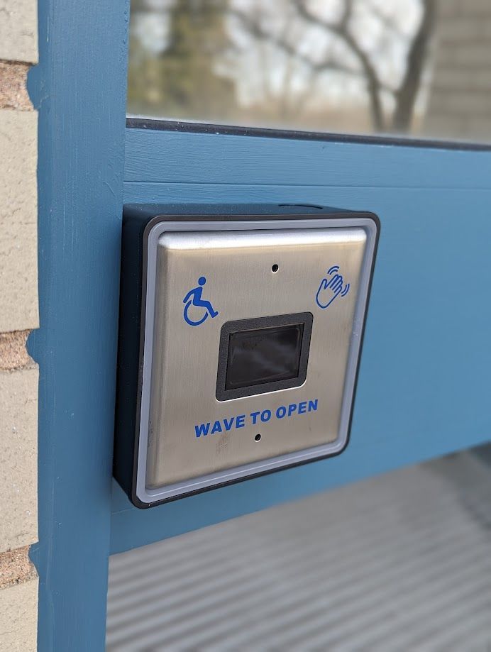 A wave to open button on a blue door