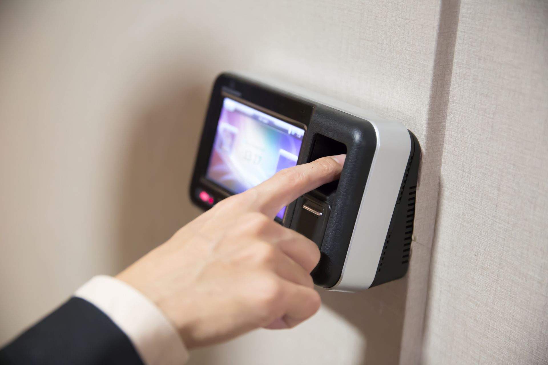 A person is using a fingerprint scanner on a wall.