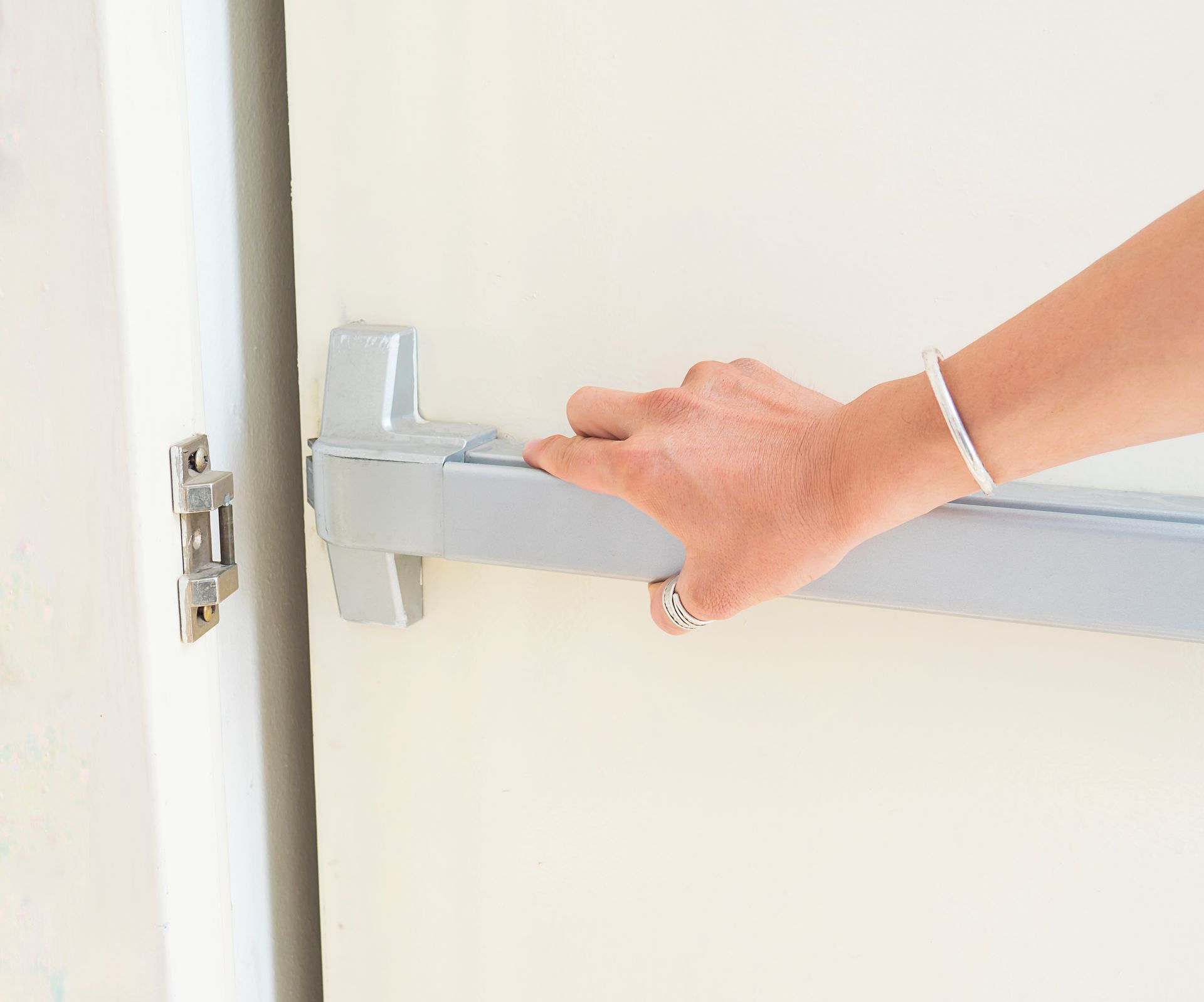 a woman is opening a door with a panic bar