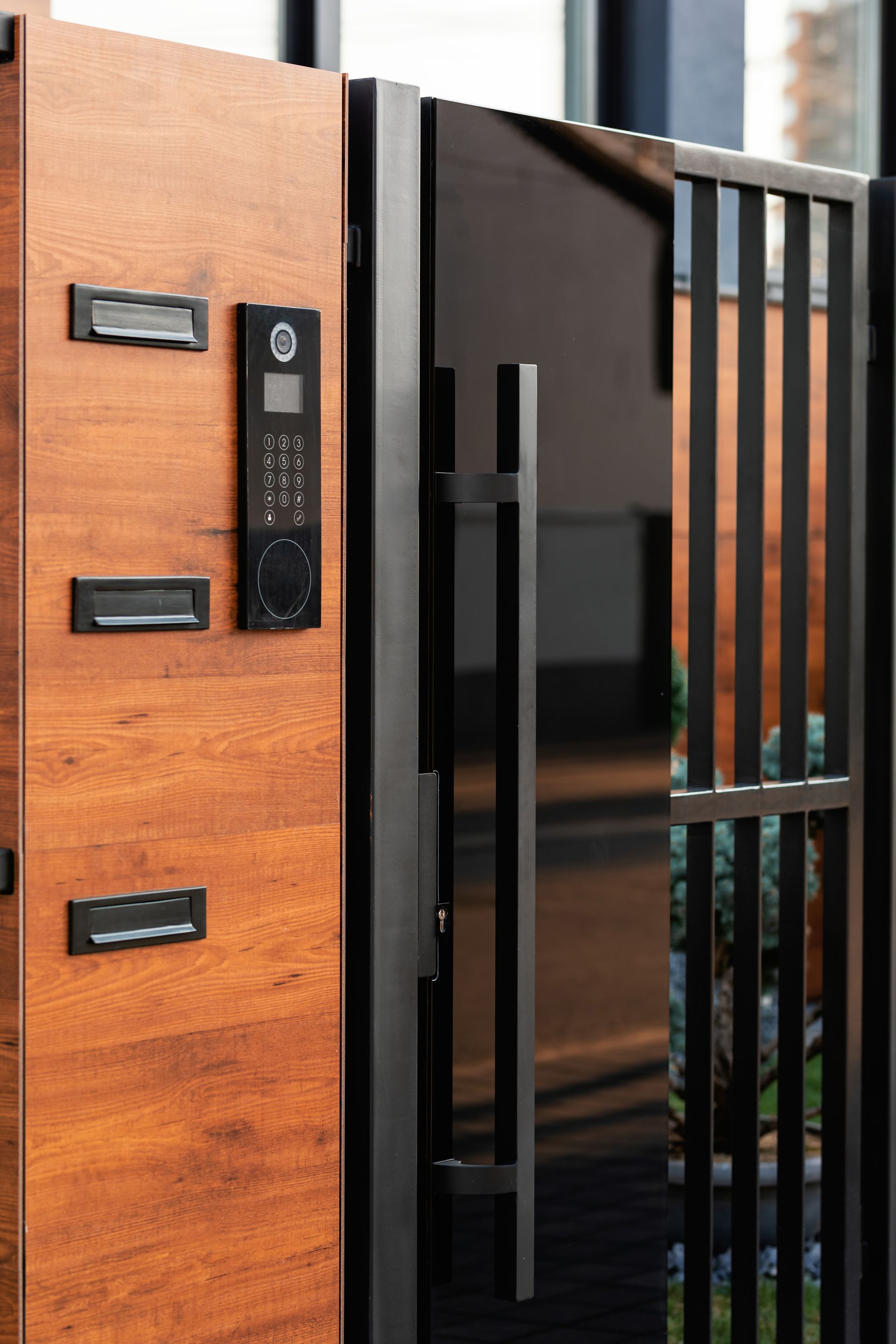 a wooden door with a black handle is behind a black fence .