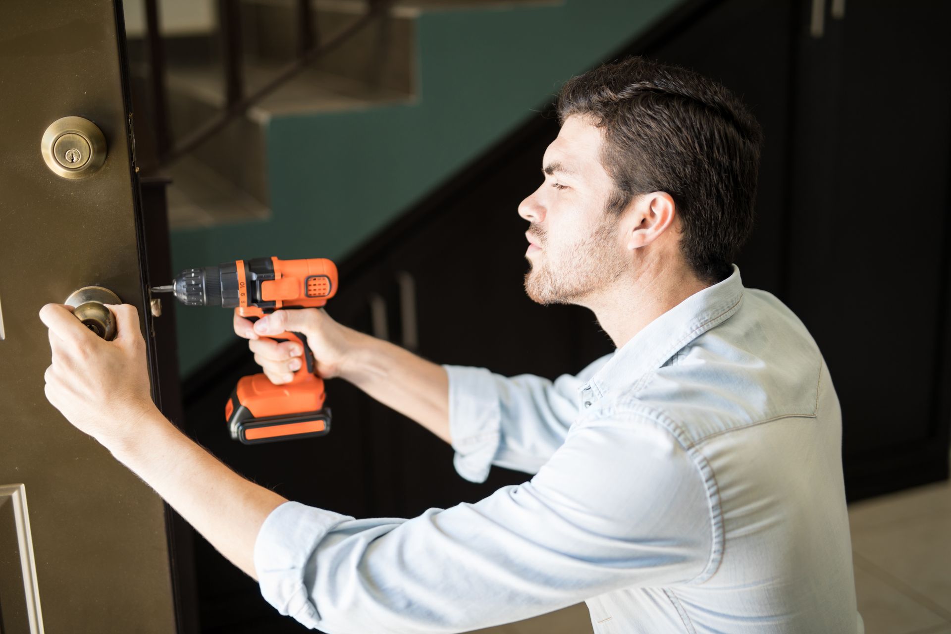 A man is fixing a door with a drill.