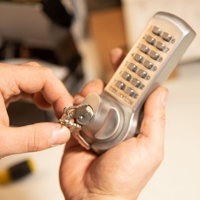 a person is holding a combination lock with a key in their hand