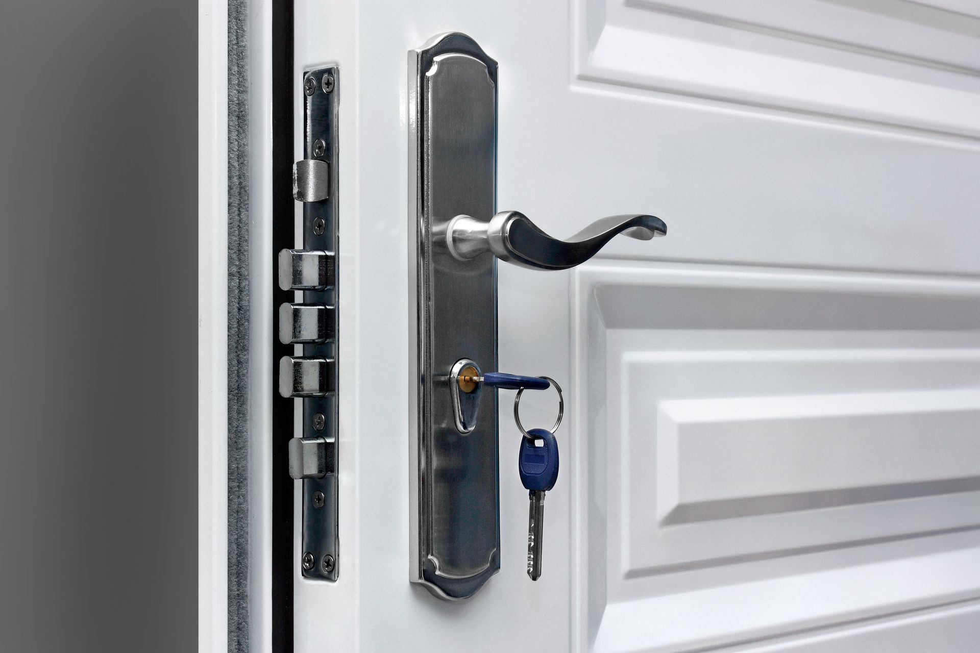 White door with silver handle, key in the lock, and security bolts.