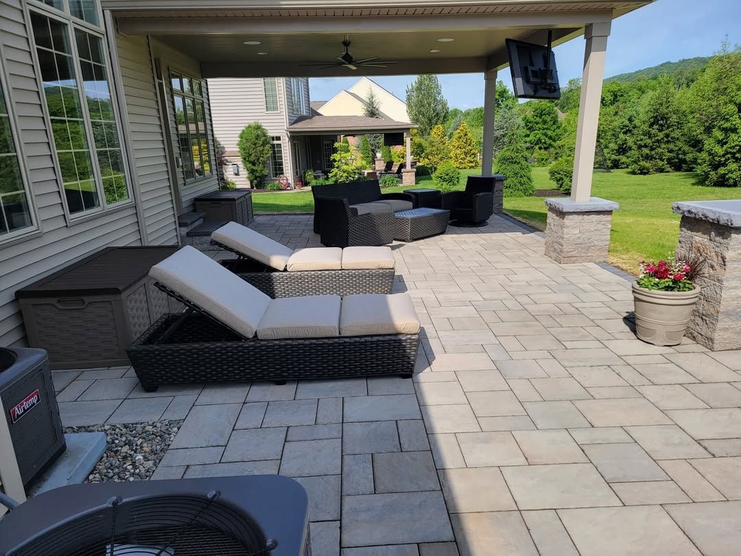 Jesse James Hardscaping - Patio with lounge chairs, furniture, and a view of a house and green landscape.