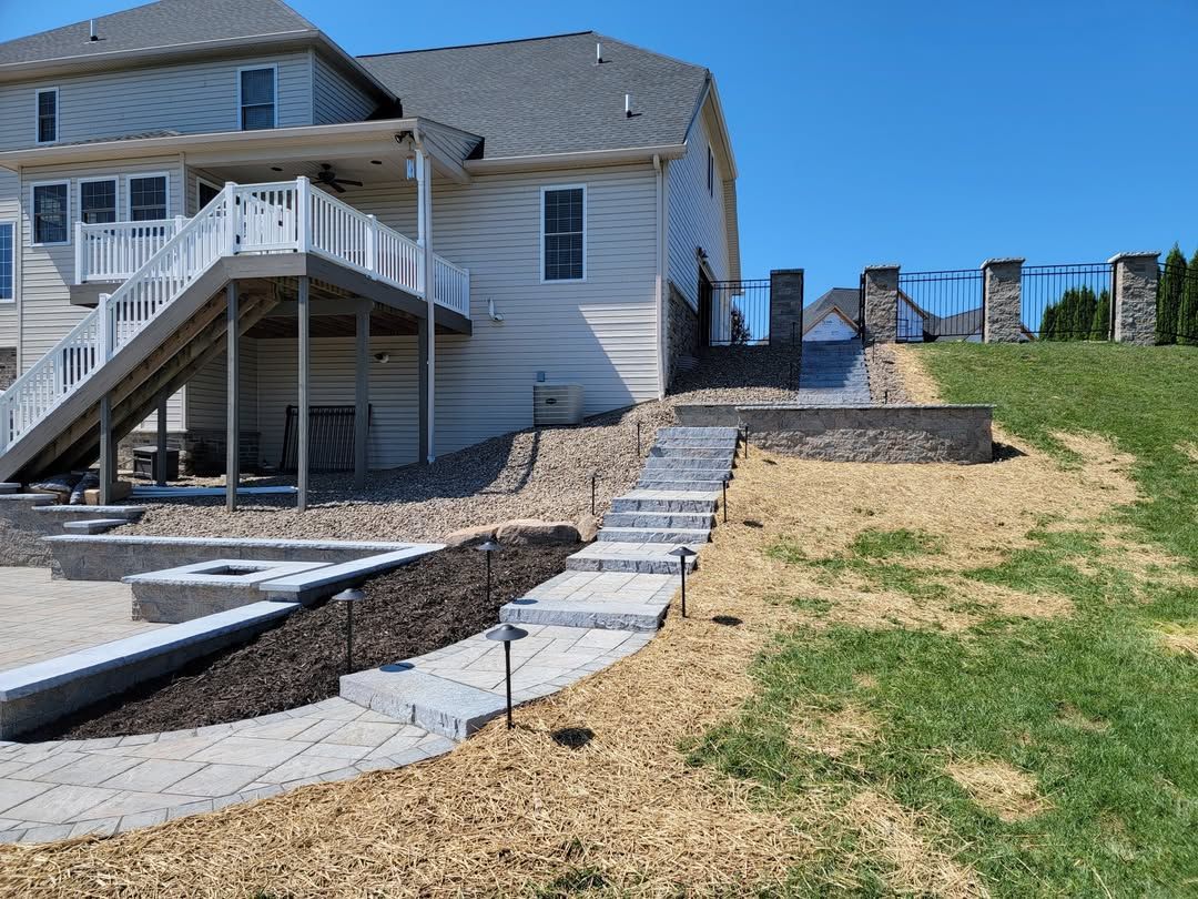 Jesse James Hardscaping - Image -Backyard with stairs, retaining walls, and deck on a sunny day.