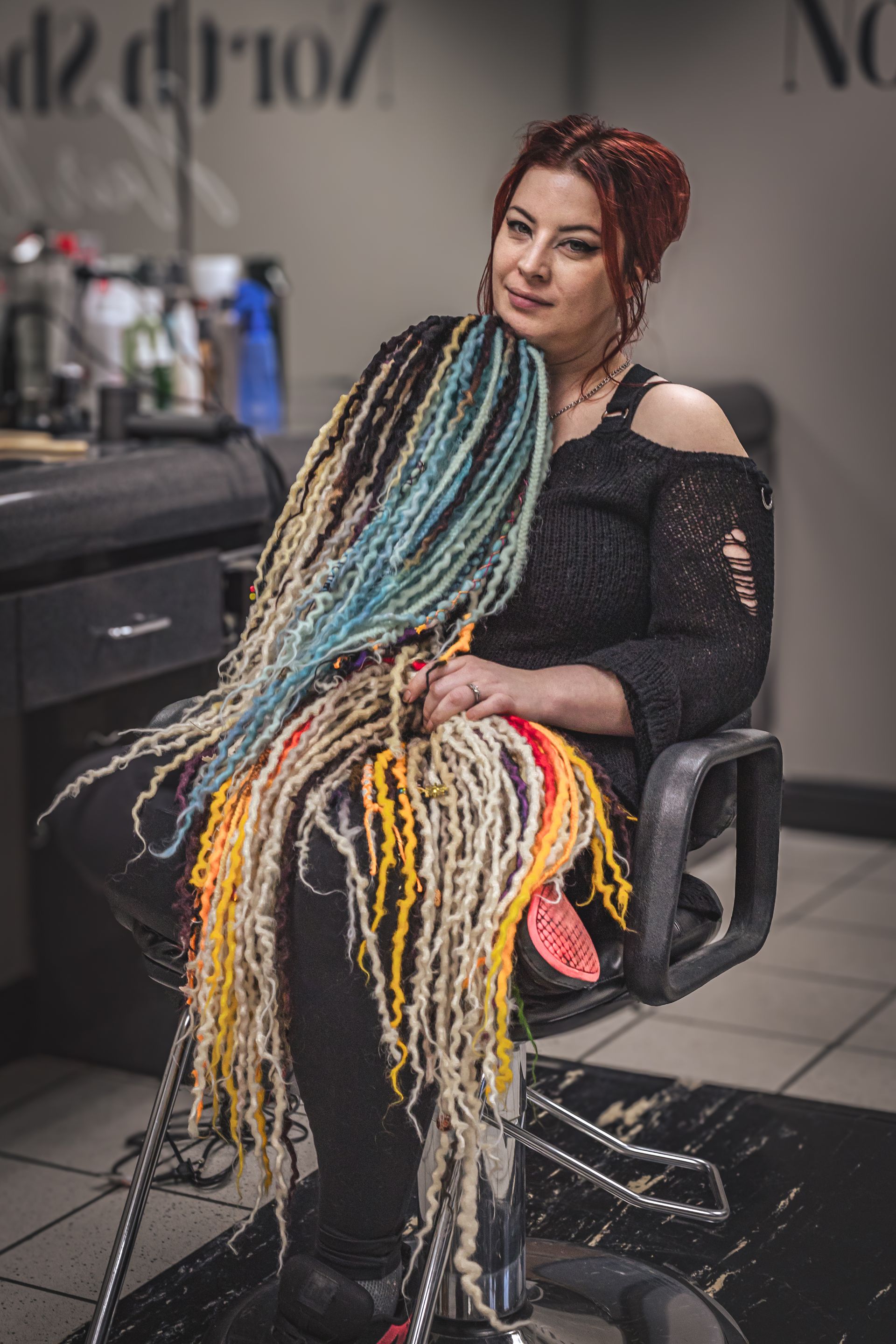 A woman with dreadlocks is sitting in a chair in a salon.