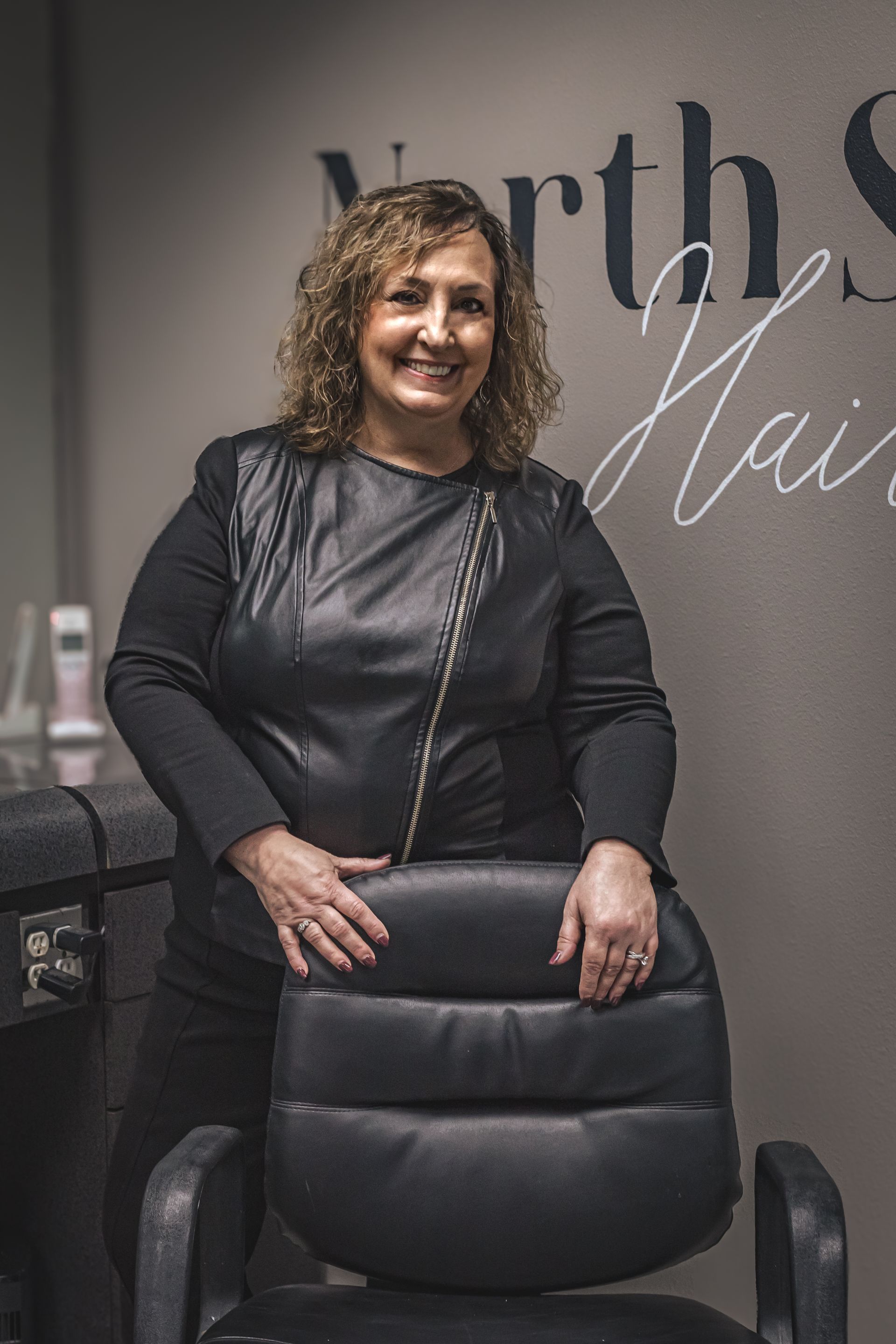 A woman is standing next to a chair in a salon.