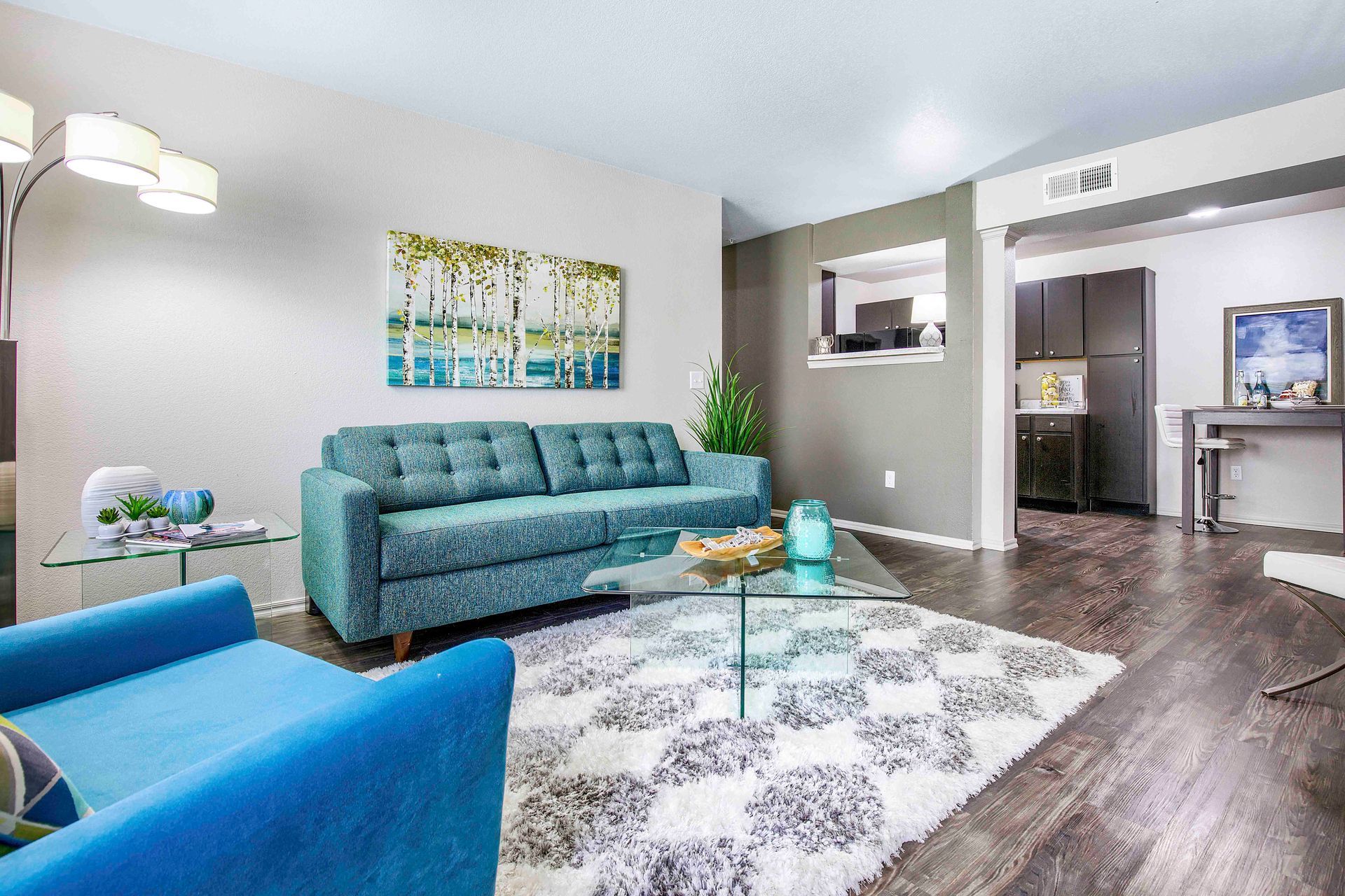 a living room with a blue couch and a glass coffee table