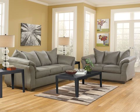 Living room with gray sofas, a dark wood coffee table, and cream-colored walls. Brown and beige patterned rug on the floor.