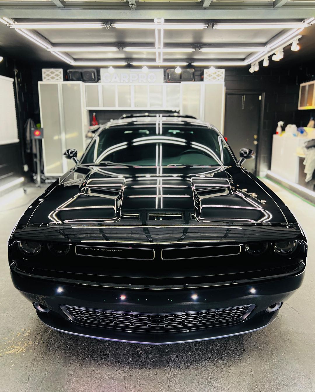 A black dodge challenger is parked in a garage.