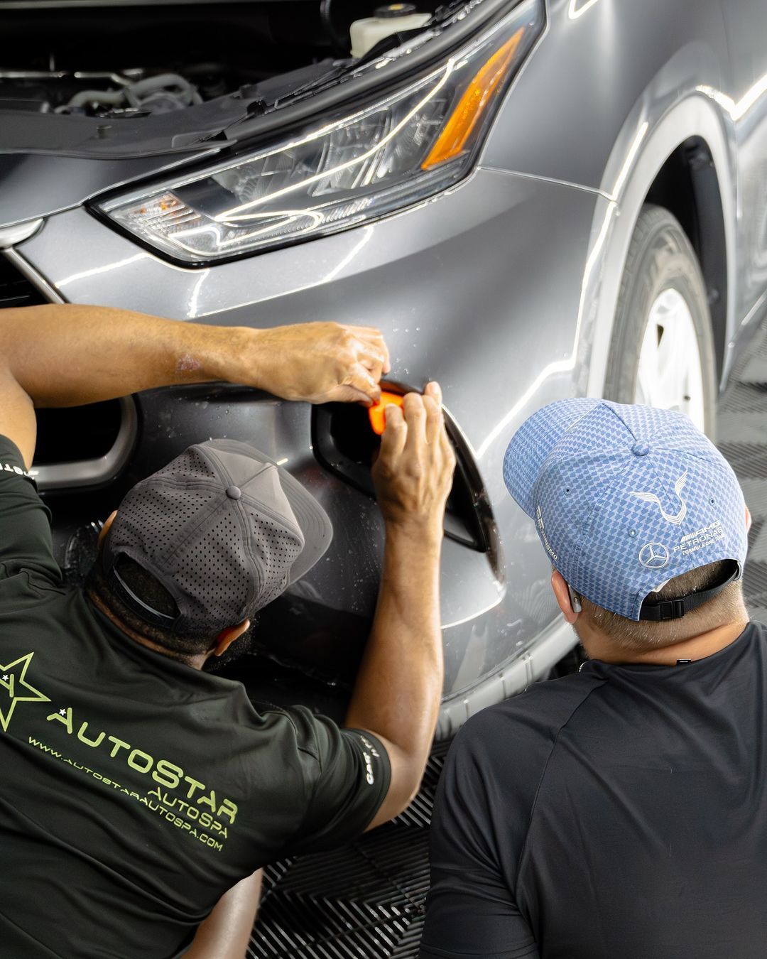 Two men are working on a car in a garage.