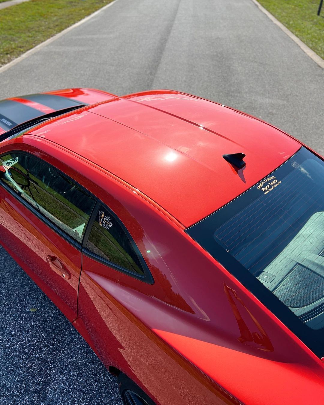 A red car is parked on the side of the road