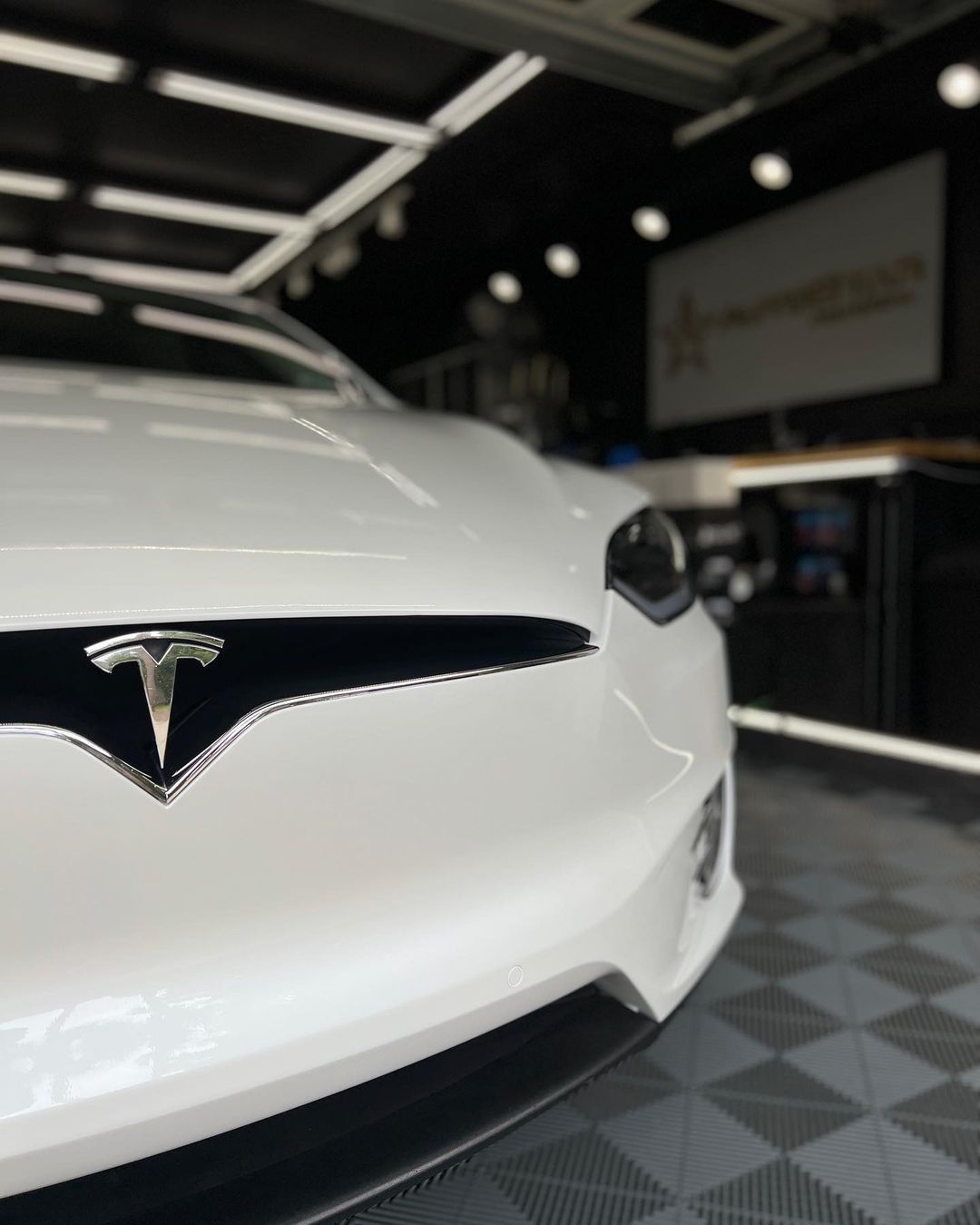 A white tesla model s is parked in a garage