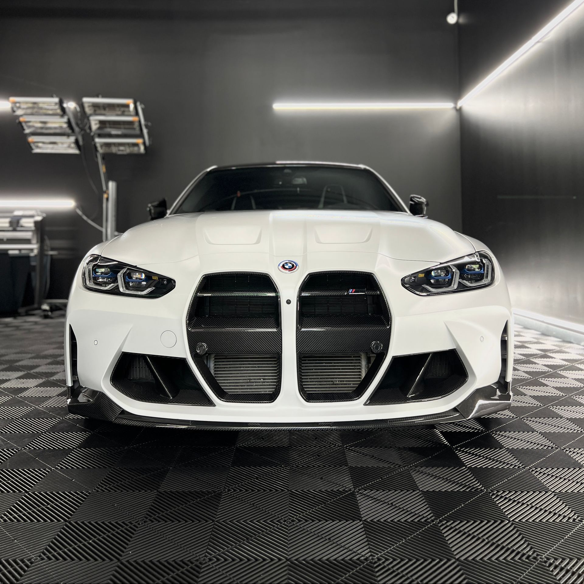 A white bmw m4 is parked in a garage.