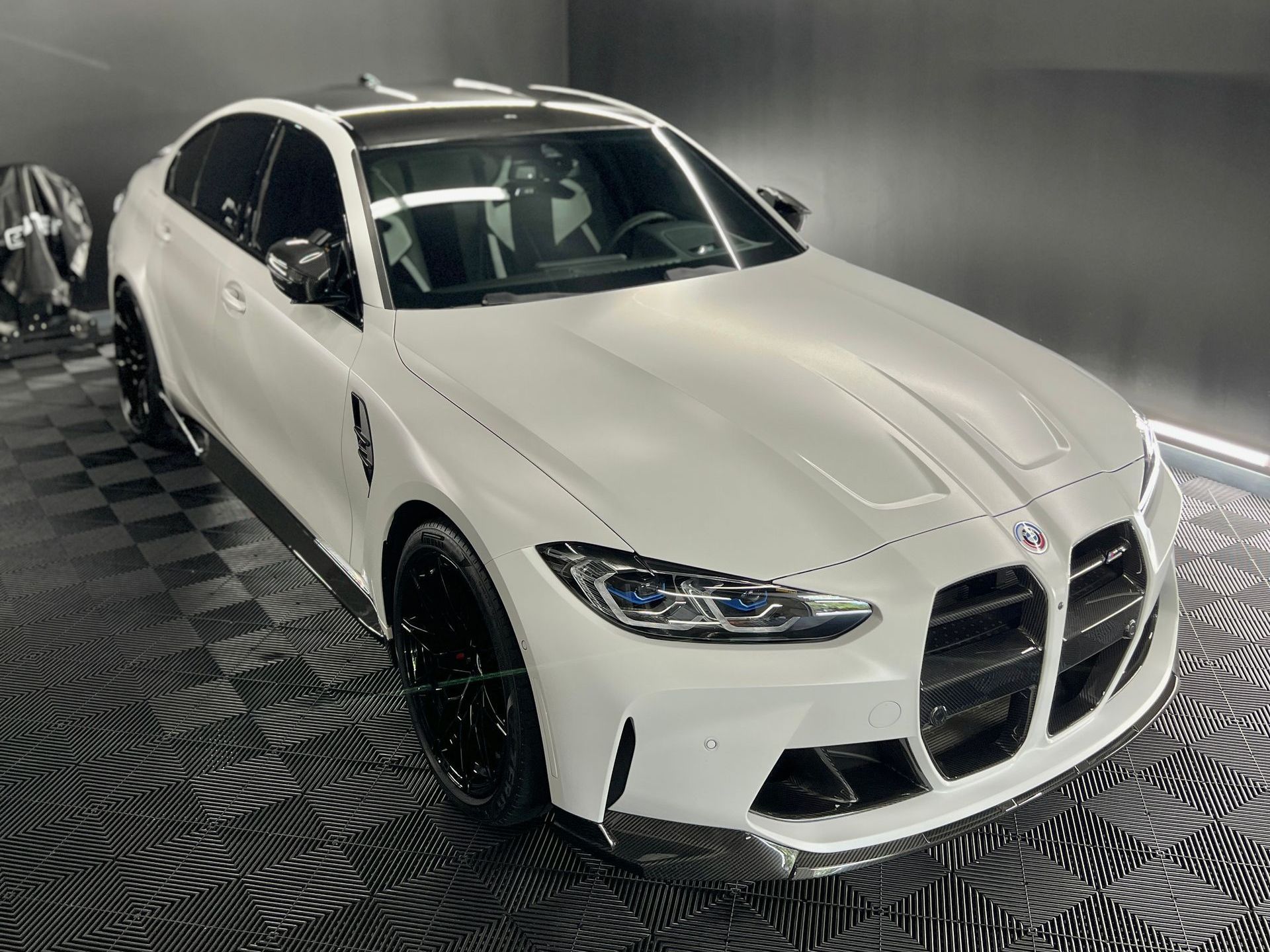 A white bmw m3 is parked in a garage.