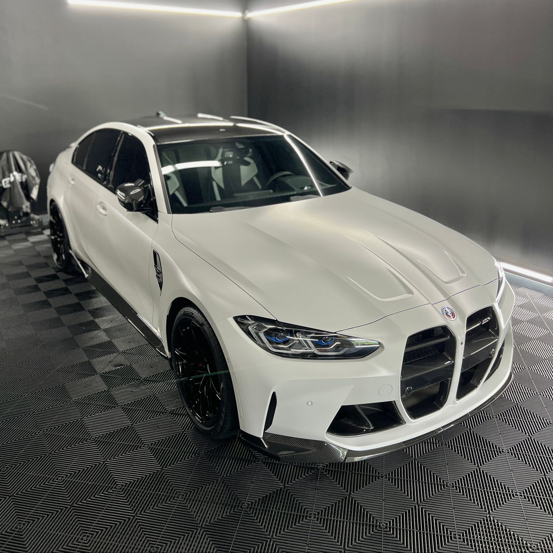 A white bmw m3 is parked in a garage.