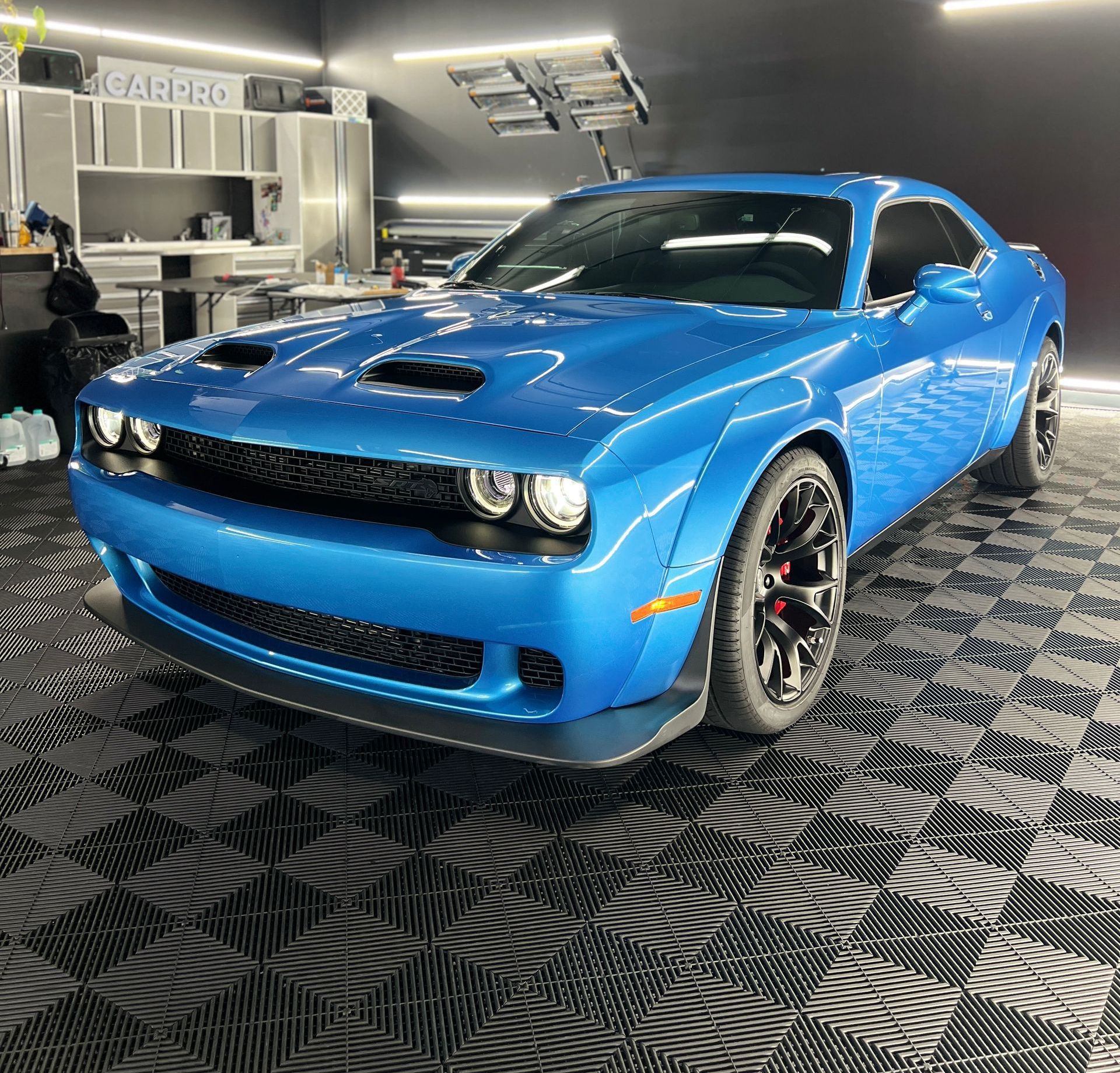 A blue dodge challenger is parked in a garage