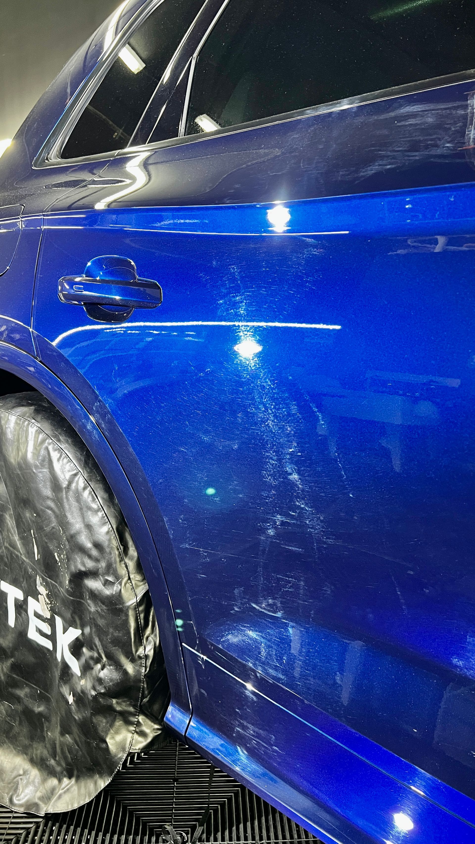 A close up of a blue car being washed in a car wash.