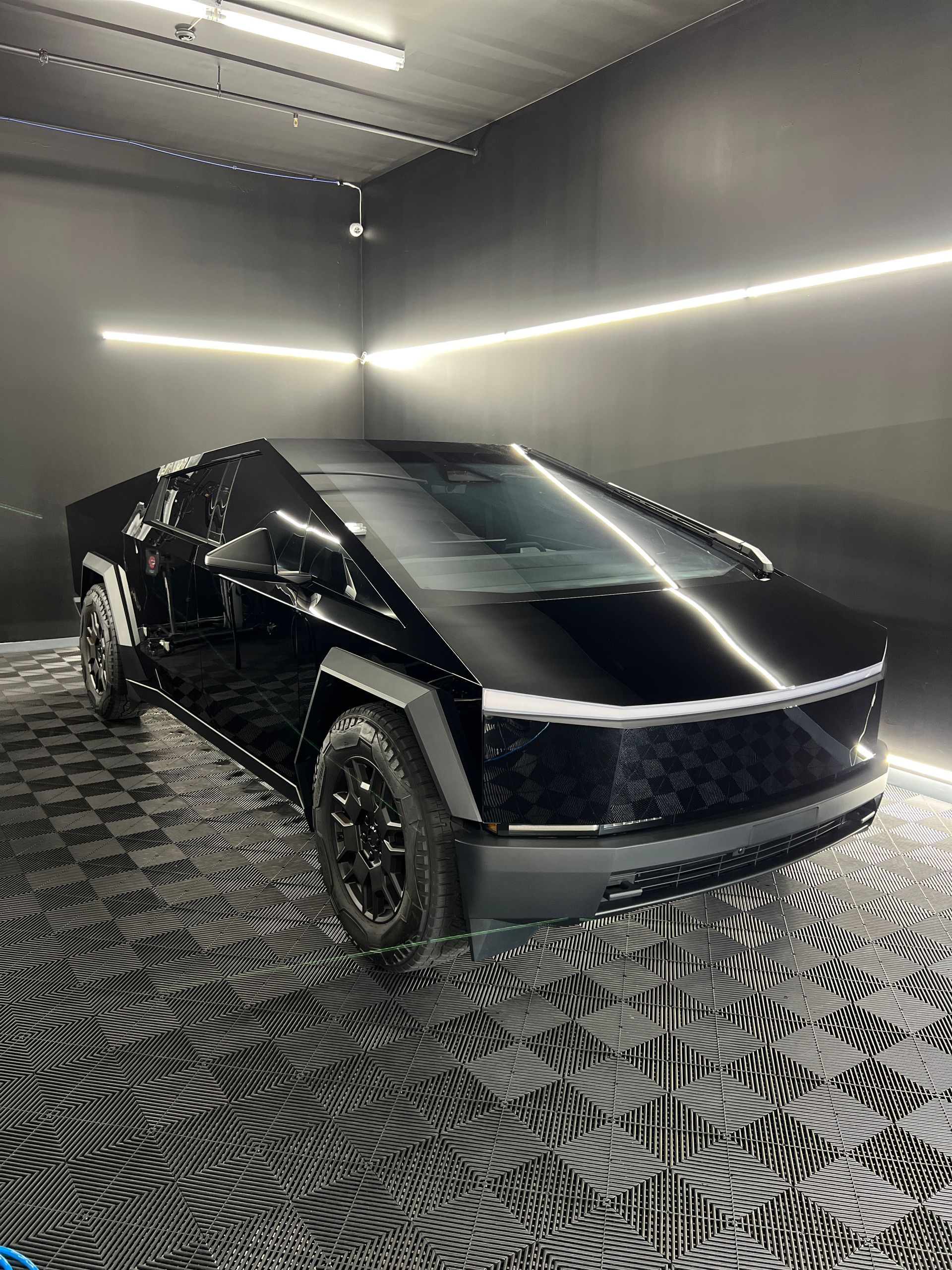 A black tesla cybertruck is parked in a garage.