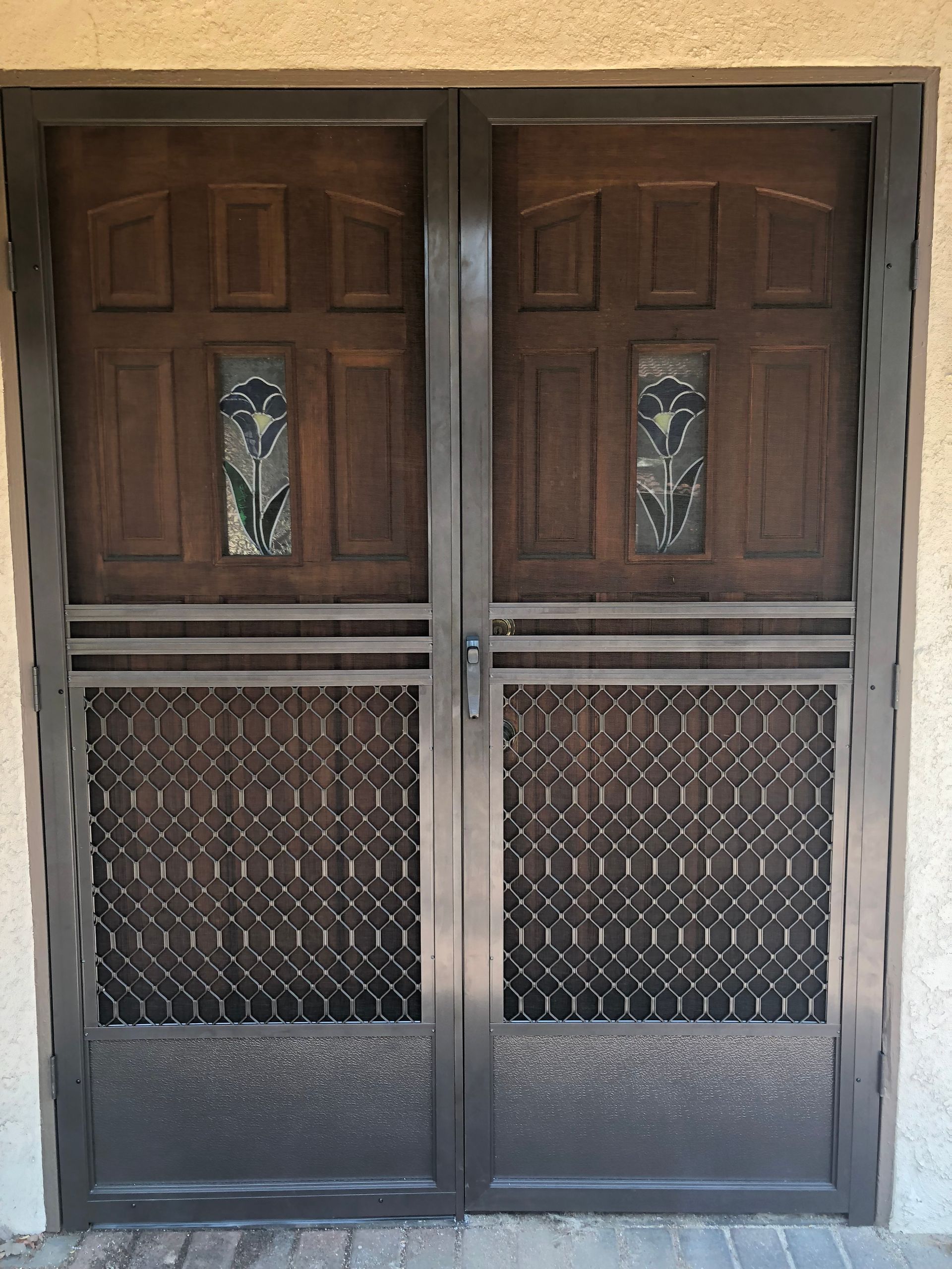 Wooden double front doors with decorative screen panels installed