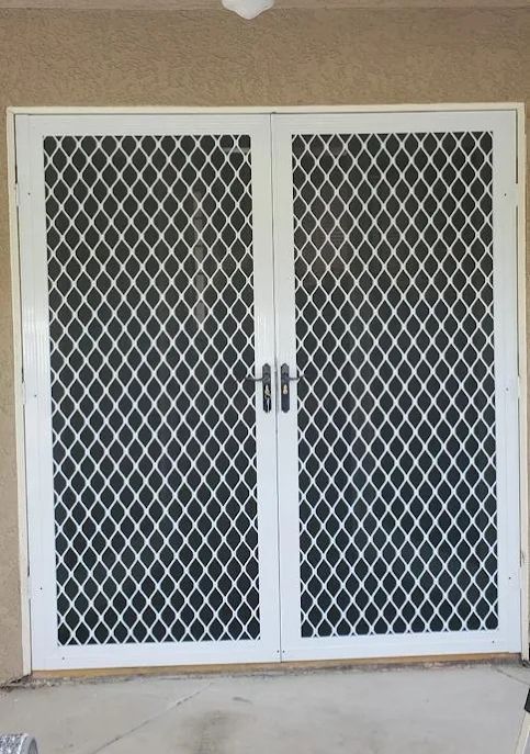 Double door with security screen and white trim under an awning.