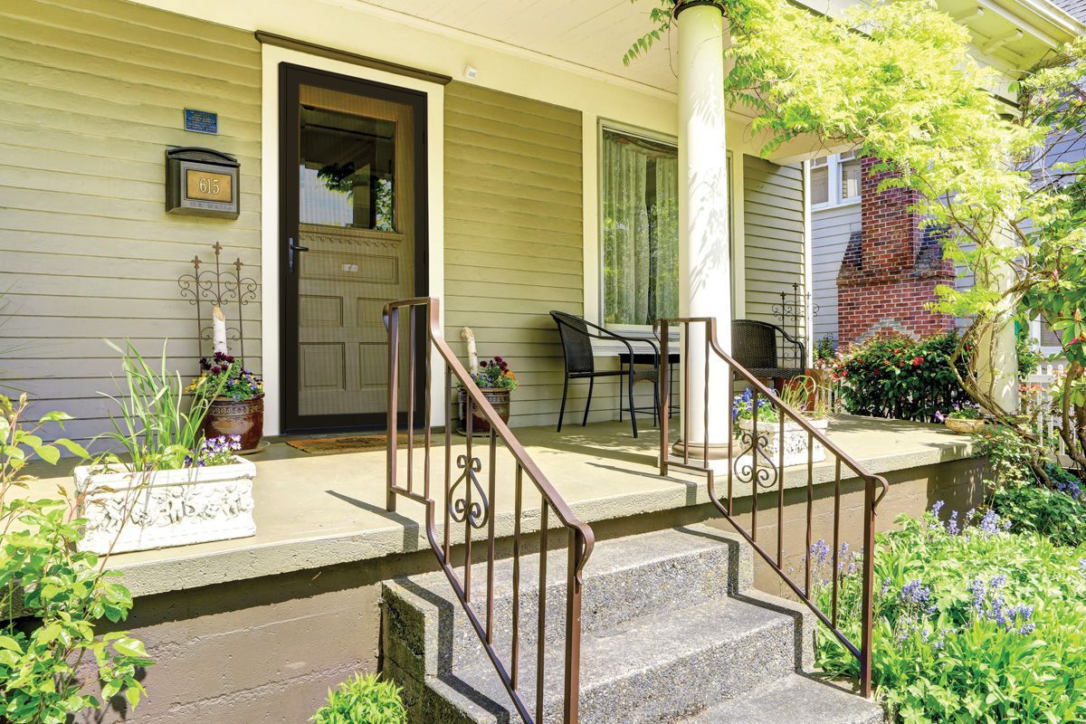 Exterior view of a house with a porch. Steps lead up to the porch with a front door and plants.