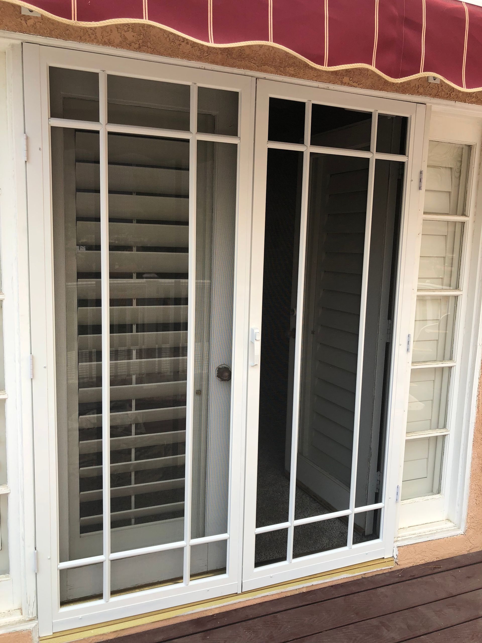 Sliding glass door with a white-framed screen door and awning above