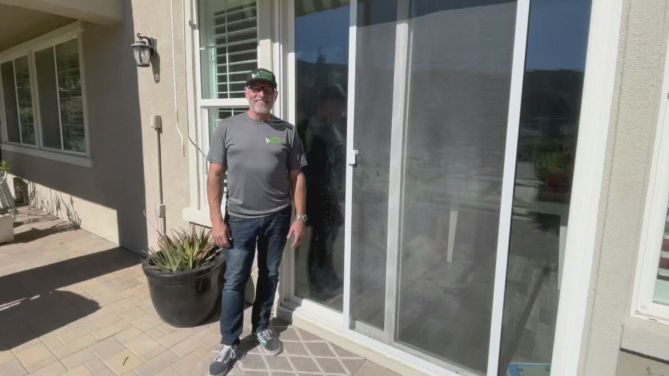 Man standing next to a sliding screen door on a residential patio