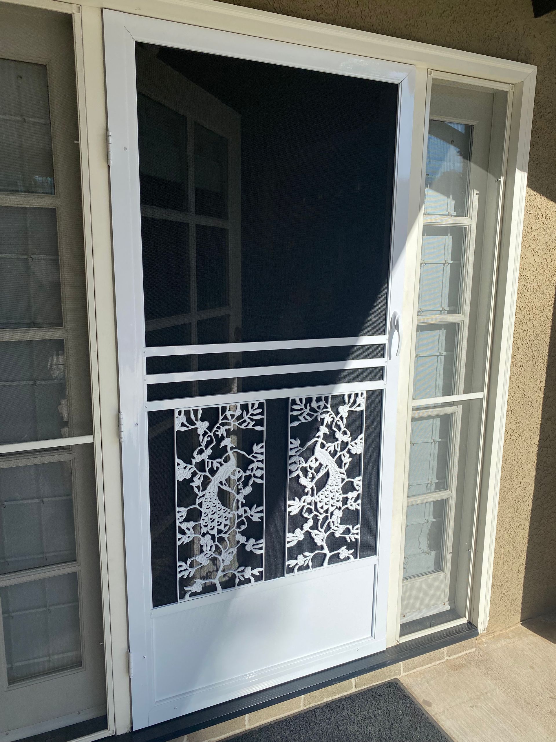 Open front door with a white security screen door featuring decorative metalwork
