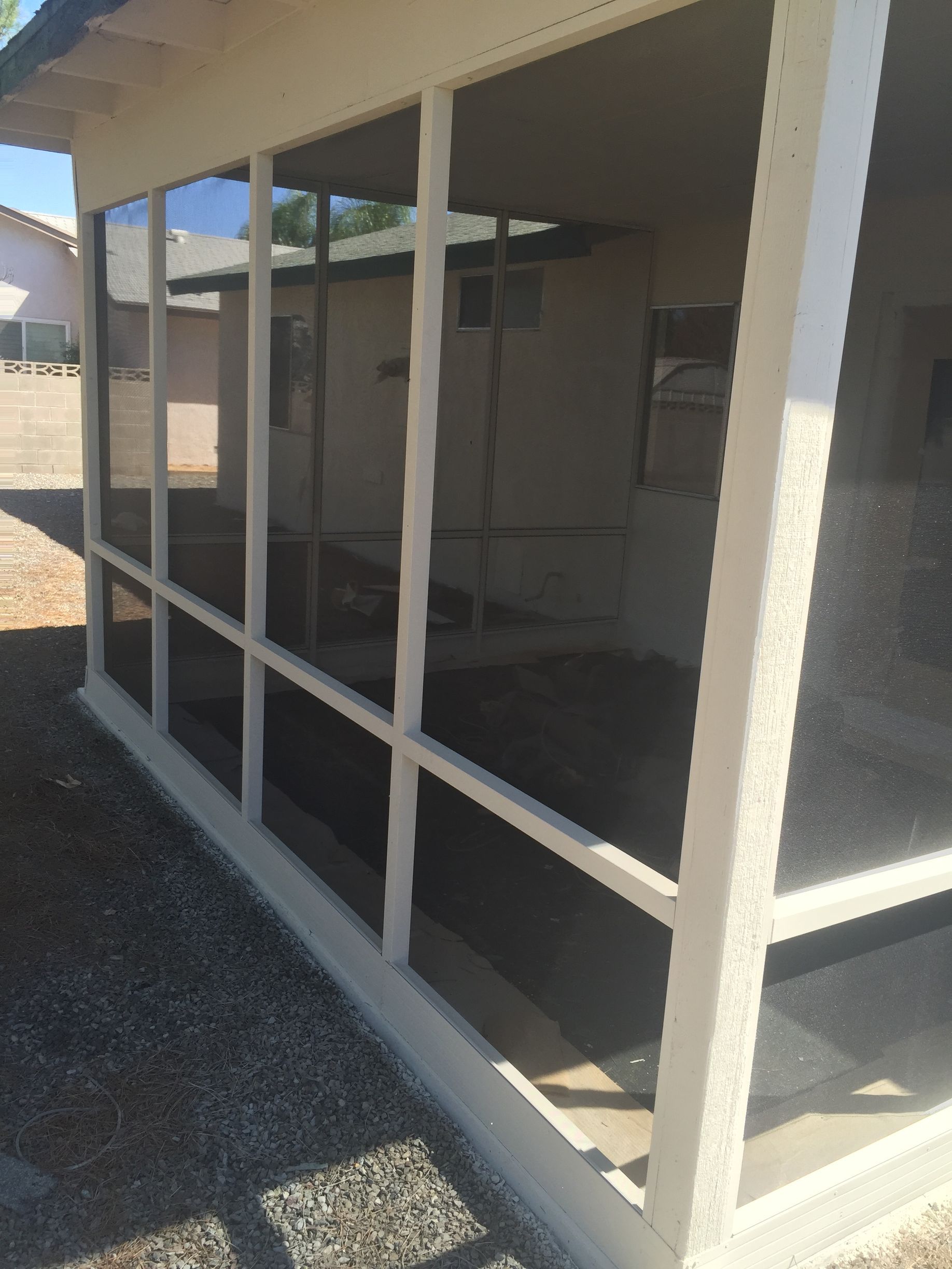 Side view of a screened patio enclosure along a narrow walkway