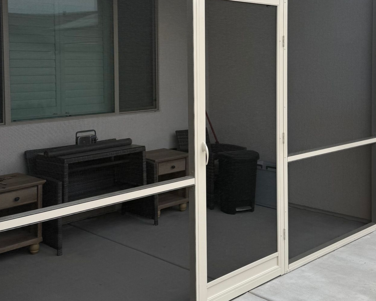 Dog at an open door, looking at the camera. Beige walls, window to the right, wreath on the door.