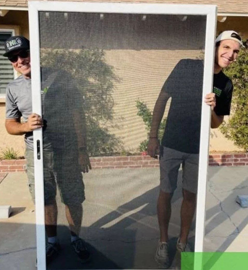 Technician installing or adjusting a sliding screen door on a patio