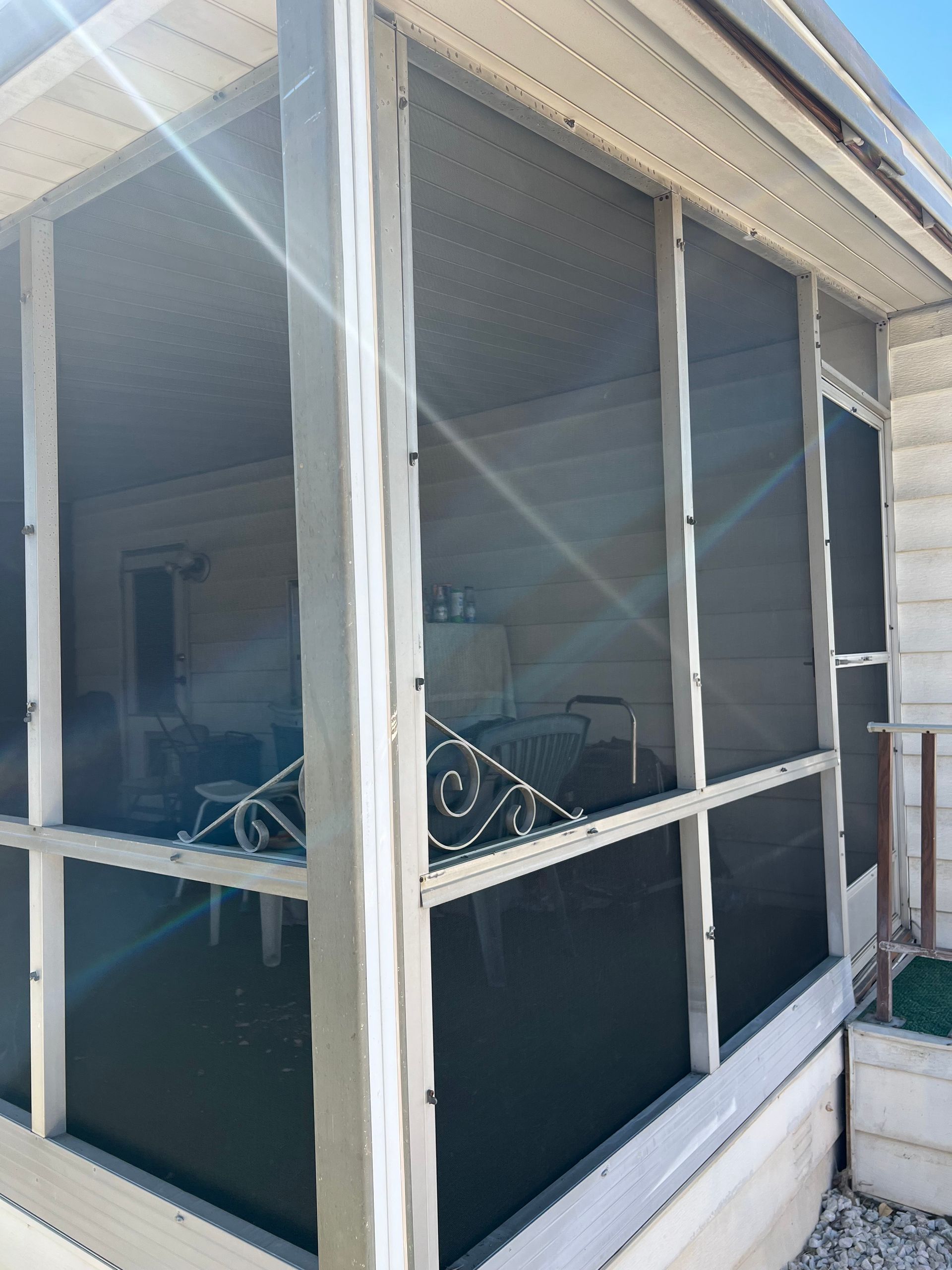 Corner view of a screened patio enclosure with dark mesh panels