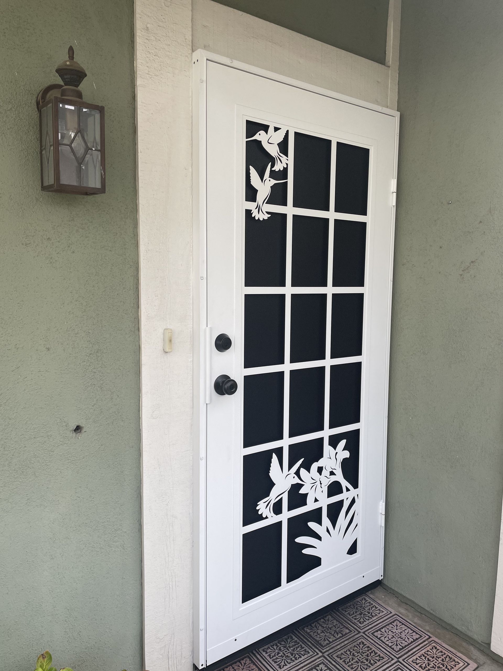 White security screen door with decorative metal design at a front entry
