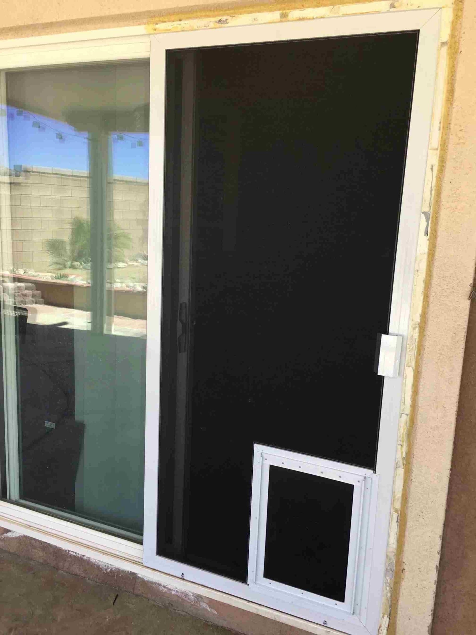 Window screen frame with dark mesh and a small pet door installed