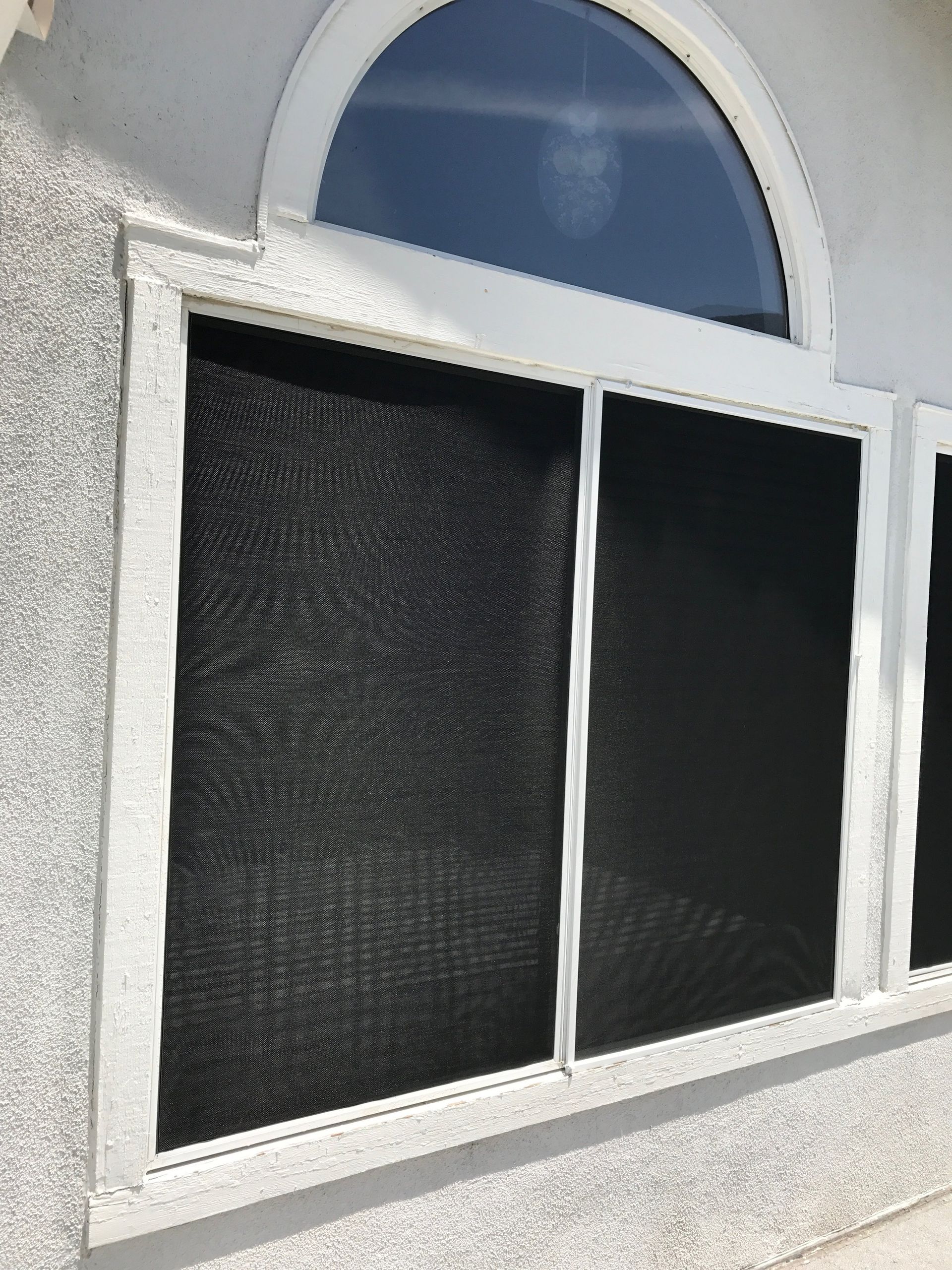 Arched window with installed dark solar screen mesh