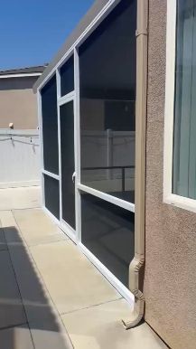 Side view of a screened patio enclosure along a residential walkway